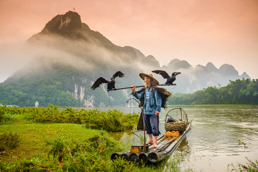 pescador en su lancha por el rio cormoran en la region de Yangshuo